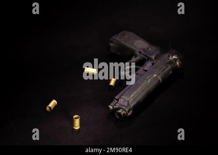 Pistol with 9mm shell casings on black background, macro shot Stock Photo