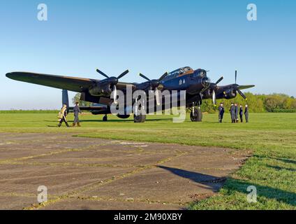 AVRO Lancaster bomber 'Just Jane', under restoration at Lincolnshire Aviation Heritage Centre with renactors as crfew checking their aircraft. Stock Photo