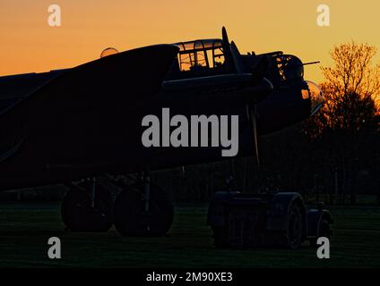 AVRO Lancaster bomber 'Just Jane', under restoration at Lincolnshire Aviation Heritage Centre silhouetted against a sunset. Stock Photo