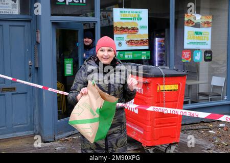 Hastings, East Sussex, 16 January 2023. Heavy rain and blocked storm drain to the sea causes major flood in Hastings Town Centre, closing Priory Meadow shopping centre and flooding homes and businesses. Agi from Subway sandwich shop gives away bread to passers-by. C.Clarke/Alamy Live News Stock Photo