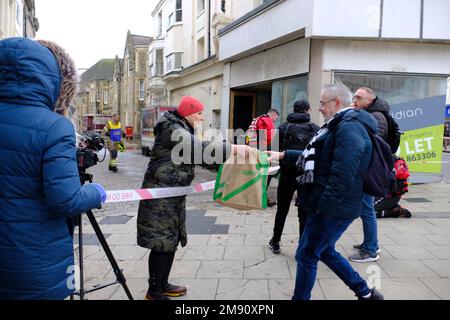 Hastings, East Sussex, 16 January 2023. Heavy rain and blocked storm drain to the sea causes major flood in Hastings Town Centre, closing Priory Meadow shopping centre and flooding homes and businesses. Agi from Subway sandwich shop gives away bread to passers-by. C.Clarke/Alamy Live News Stock Photo