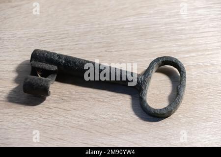 An old rusty key on a wooden table Stock Photo