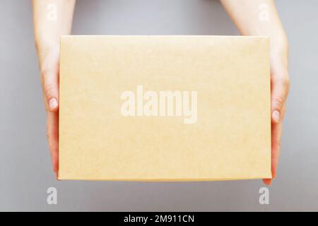 The human hands holding delivers carton box on the grey background. copy space for text. Delivery and online shopping concept Stock Photo