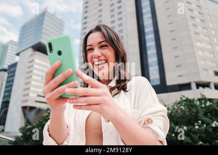 Young caucasian woman smiling searching sale on internet using online shopping app. One happy brunette lady excited using the cellphone. High quality photo Stock Photo