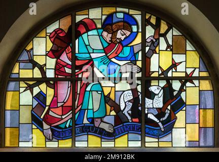 TASCH, SWITZERLAND - JULY 2, 2022: The stained glass with the Jesus as Good Shepherd in the parish church designed by August Wanner Stock Photo