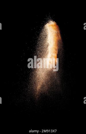 Some brown particles exploding on black background, brown dust splashing Stock Photo