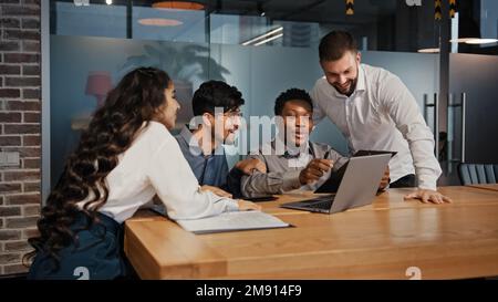 Business partners multiracial team group people workers in office looking at laptop happy with internet work success project opportunity multinational Stock Photo