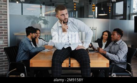 Thoughtful pensive man leader boss businessman company CEO sitting on office table thinks about solving problem difficult decision considering project Stock Photo