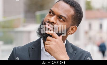 Ethnic bearded African American man entrepreneur pensive manager executive thoughtful worker employer ponder think about business problem solution Stock Photo