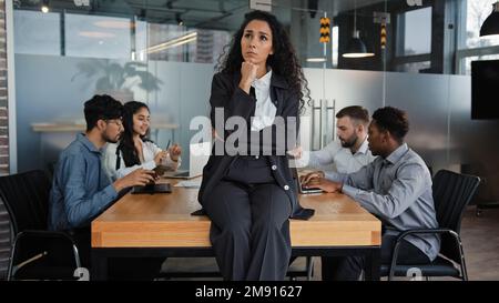 Pensive thinking thoughtful businesswoman female leader boss woman sitting on table in boardroom think about project idea on background of Stock Photo