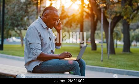 African American middle-aged ethnic man professional businessman freelancer entrepreneur employer talking with smartphone talk to client help by phone Stock Photo