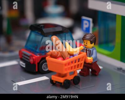 Tambov, Russian Federation - January 14, 2023 A Lego businessman minifigure pushing a shopping cart full of groceries to his car. Stock Photo