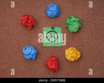 A green paper note with sad face on a cork board. Depression concept. Stock Photo