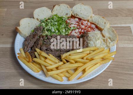 Bistro dishe culinary Still Life. Kefta with salad, tomato accompaniement onion, french fries and slice of bread Stock Photo