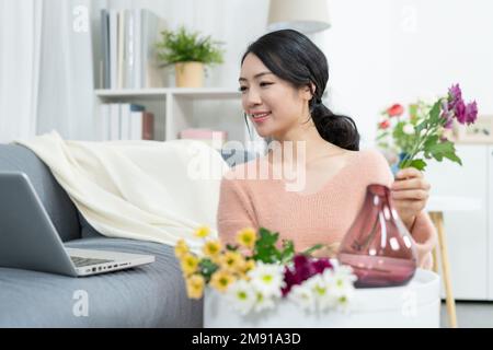The young woman at home arranging flowers Stock Photo