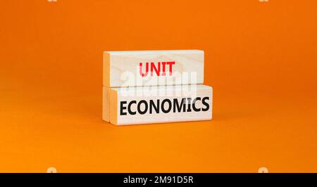 Unit economics symbol. Concept words Unit economics on wooden blocks. Beautiful orange table orange background. Business and unit economics concept. C Stock Photo