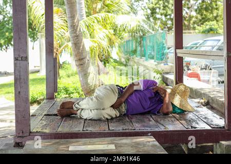 Georgetown, Penang, Malaysia - November 2012: A worker wearing a straw hat taking a nap on a wooden platform by the roadside in the heritage town of P Stock Photo