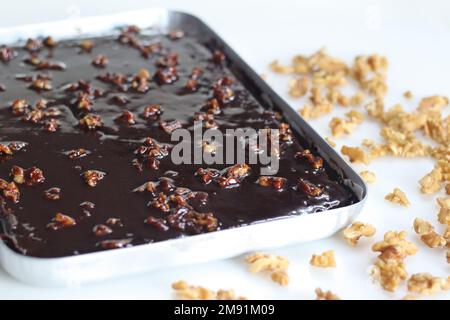 Texas Sheet Cake in baking pan. It is a large, thin chocolate cake topped with a rich chocolate walnut frosting. It's moist and fluffy, with a hint of Stock Photo