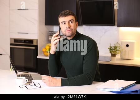 Serious man calling by phone from home office Stock Photo