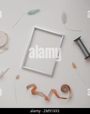 minimal mockup with blank frame with sewing thread and sewing items on white background, flatlay, top view, copy space Stock Photo