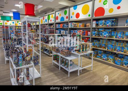 Colorful interior of Macy's toy department. Rack with various boxes of toy models in front. New York. Stock Photo