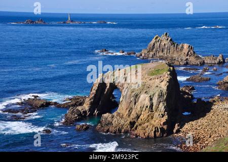 View towards the Longships lighthouse off Lands End in Cornwall, from the South West Coast path with Enys Dodnan and the Armed Knight rocks in the for Stock Photo