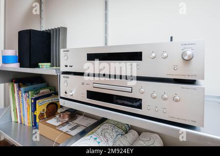 Paris, France - Dec 13, 2022: new Onkyo NS-6170 network audio player with DSD Hi-Res Audio and DSD DAB WIFI device above Onkyo C-7070 luxury CD player - all on a Vitsoe 6060 shelves children books in background Stock Photo