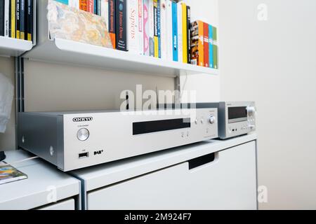 Paris, France - Dec 13, 2022: POV male hand pointing to Chromecast built-in, certified sign on new Onkyo NS-6170 network audio player with DSD Hi-Res Audio and DSD DAB WIFI device carpet rug silk background Stock Photo