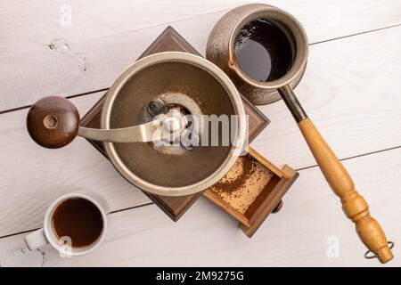 Manual coffee grinder on a white painted wooden table, top view. Stock Photo