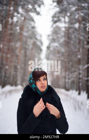 Russian girl in coat and scarf in cold winter in the woods Stock Photo