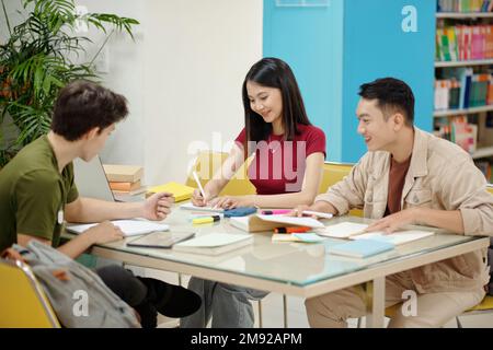 Group of joyful high school students doing homework together Stock Photo