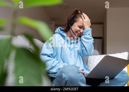 Young woman student in headset studying online course using laptop and having fun during lesson. Stock Photo