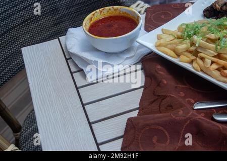 Barbecue chicken thighs with baked potatoes on wooden table at the restaurant Stock Photo