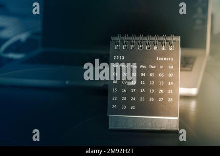 Calendar on desk next to laptop in sunlight Stock Photo