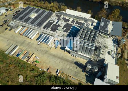 Aerial view of solar power plant with blue photovoltaic panels mounted on industrial building roof for producing green ecological electricity Stock Photo