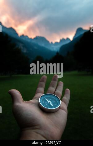 Compass held with one hand on a background mountain landscape. Concept of travel, freedom, lifestyle. Stock Photo