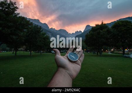 Compass held with one hand on a background mountain landscape in Dolomites. Concept of travel, freedom, lifestyle. Stock Photo