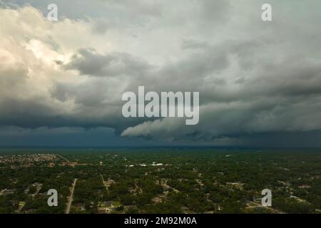 Dark stormy clouds forming on gloomy sky before heavy rainfall over suburban town area Stock Photo