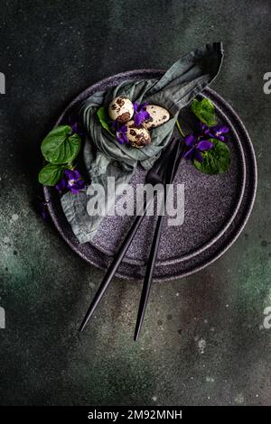 Spring table setting with wild blue viola flower on black plate set Stock Photo