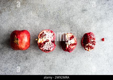 Row of organic ripe pomegranate fruits on grey stone background Stock Photo
