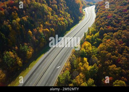 Empty free of vehicles I-40 freeway road leading to Asheville in North Carolina thru Appalachian mountains with yellow fall forest. High gas prices Stock Photo
