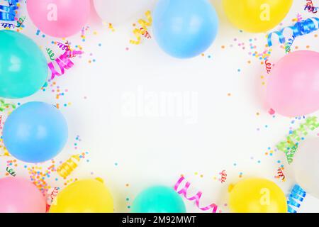 Birthday party theme frame on a white background. Top down view with balloons, confetti and streamers. Copy space. Stock Photo