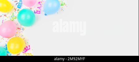 Birthday party theme banner with corner border on a white background. Overhead view with balloons, confetti and streamers. Copy space. Stock Photo