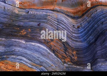Textured background of rough uneven surface of brown and purple stone wall with cracks Stock Photo