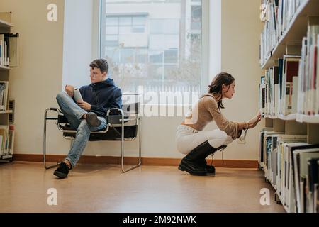 Full body of concentrated students in casual outfits preparing for exam in university library together Stock Photo