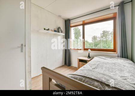 Bedside table located near bed and blank picture in light bedroom with yellow wall Stock Photo