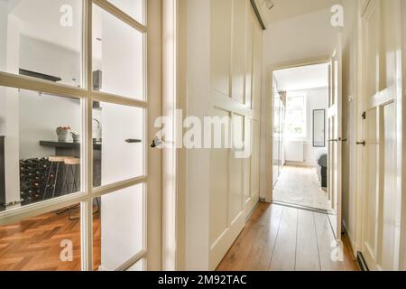 Long narrow light hallway with white walls and many closed room doors in stylish apartment at home Stock Photo
