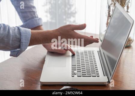 Cropped anonymous male freelancer on table using laptop and working on project in living room Stock Photo