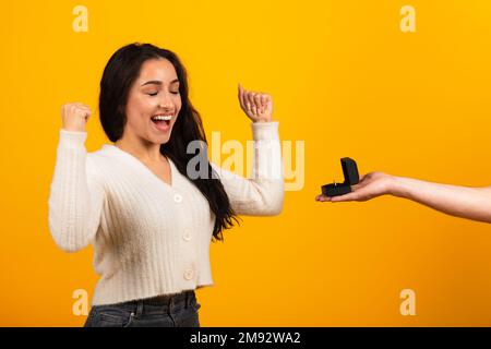 Millennial arab guy hand giving ring box to satisfied excited woman with open mouth Stock Photo