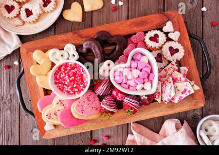 Valentines Day sweets and cookies. Above view in a serving tray over a wood background. Love and hearts theme. Stock Photo